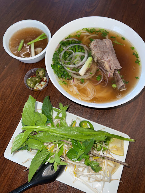 bowl and plates with pho noodle soup and toppings